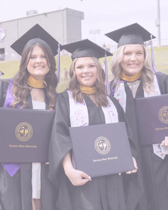 Three graduates smiling, holding diplomas, wearing caps and gowns with the logo of Tarleton State University.
