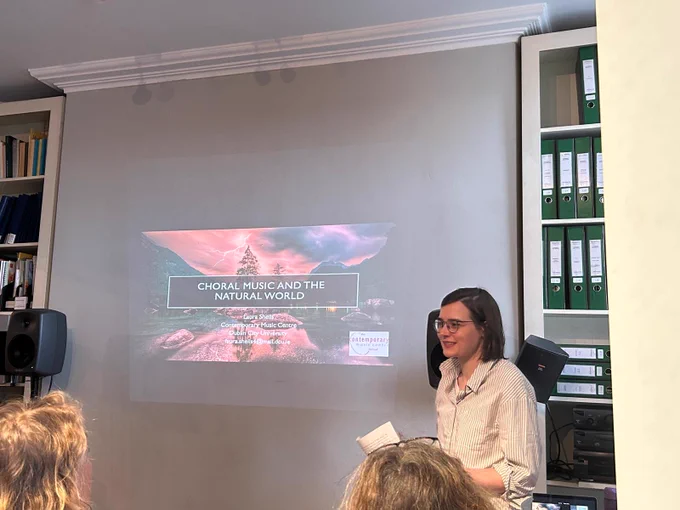 Laura Sheils presenting, with the title slide reading 'Choral Music and the Natural World'.