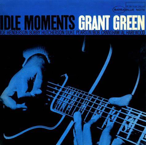Album cover for "Idle Moments" by Grant Green, featuring a close-up of hands playing a guitar set against a blue background with artist names Joe Henderson, Bobby Hutcherson, Duke Pearson, Bob Cranshaw, and Al Harewood listed.