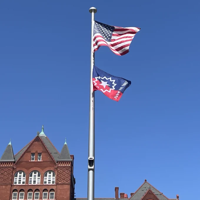 The United States and Juneteenth flags fly at Memorial Union on a clear day.