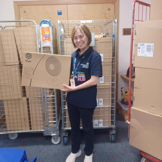 Volunteer holding a fan with boxes of fans all around her. 