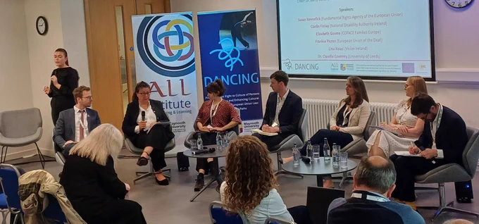 Photo of the roundtable at the conference with 6 speakers, the Chair and sign language interpreters