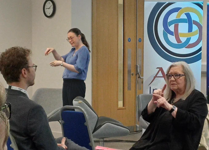 Photo of two different sign language interpreters and an attendee at the conference.