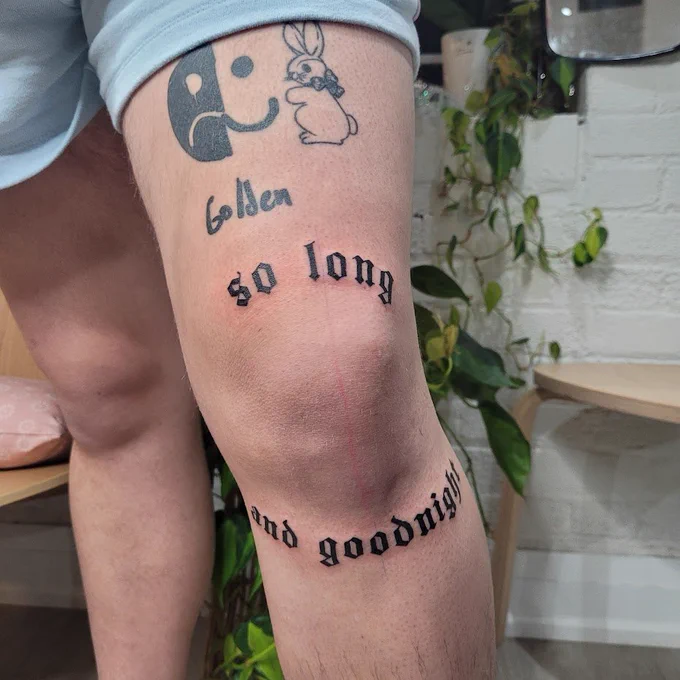 blackwork gothic text by spoopy wrapping around someone's knee cap that reads, "so long and goodnight"