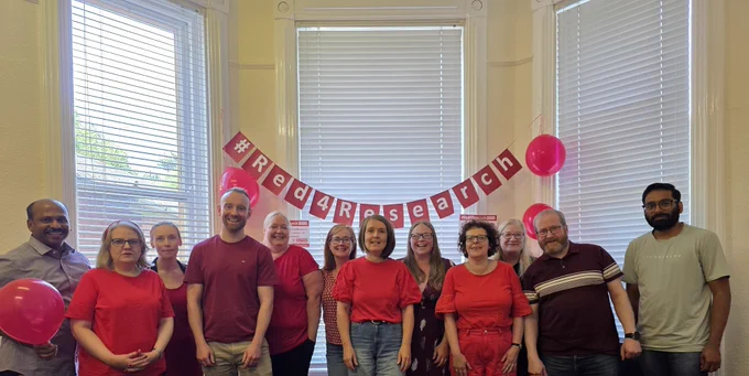 Staff in the NI Clinical Trials Unit pose in front of the Red4Research banner.