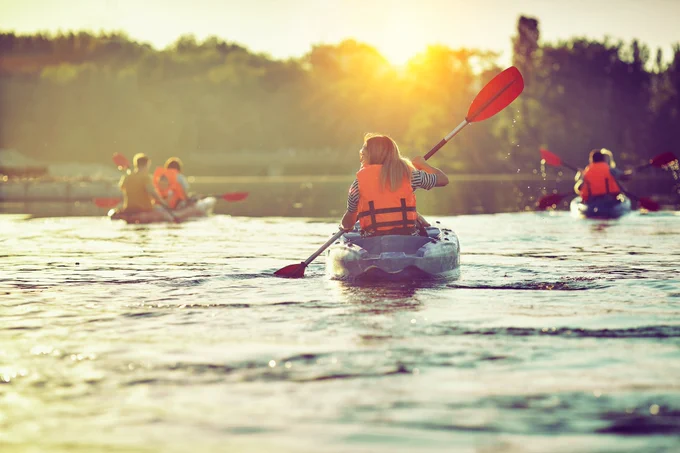 A family in orange life jackets canoeing together.