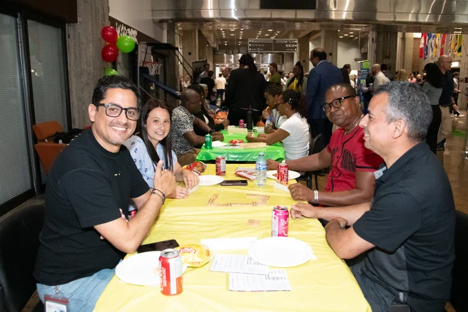 A photo showing people sitting at a table indoor, enjoying the National Public Service Week event. 