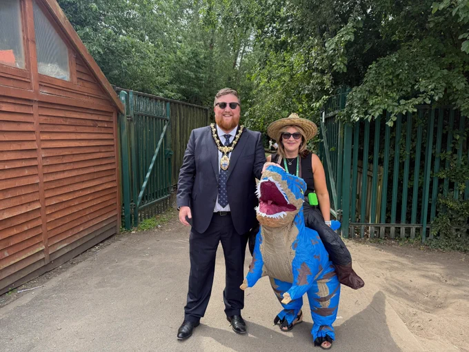 Mayor of St Helens borough, Cllr Seve Gomez-Aspron, pictured with District Primary staff wearing inflatable dinosaur costume