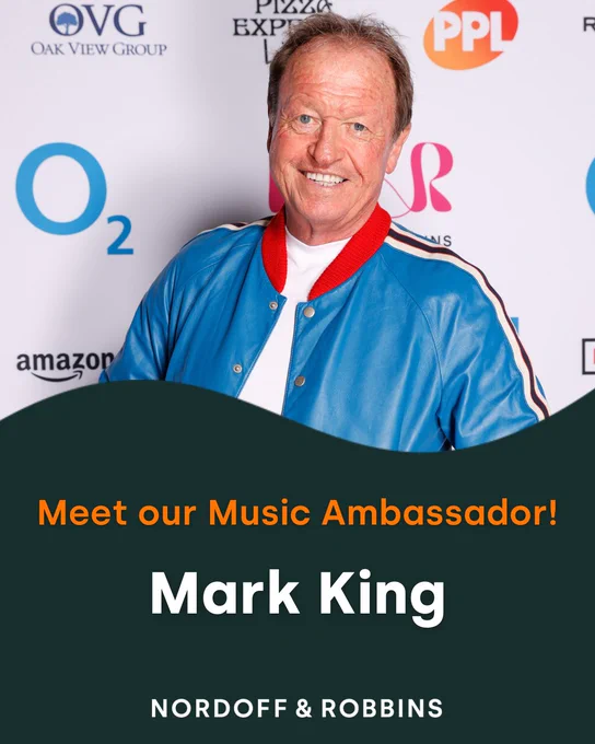 Promotional image featuring music ambassador Mark King posing in front of a sponsor backdrop at a Nordoff and Robbins event.