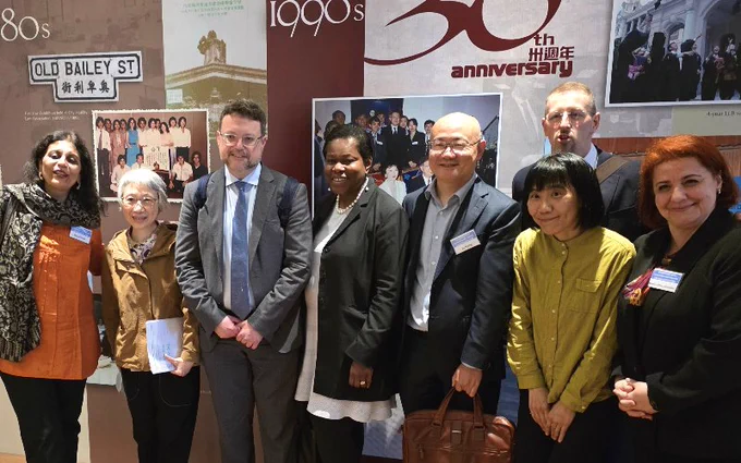 Eight smartly dressed people standing together smiling, including Professor Ioannis Lianos.