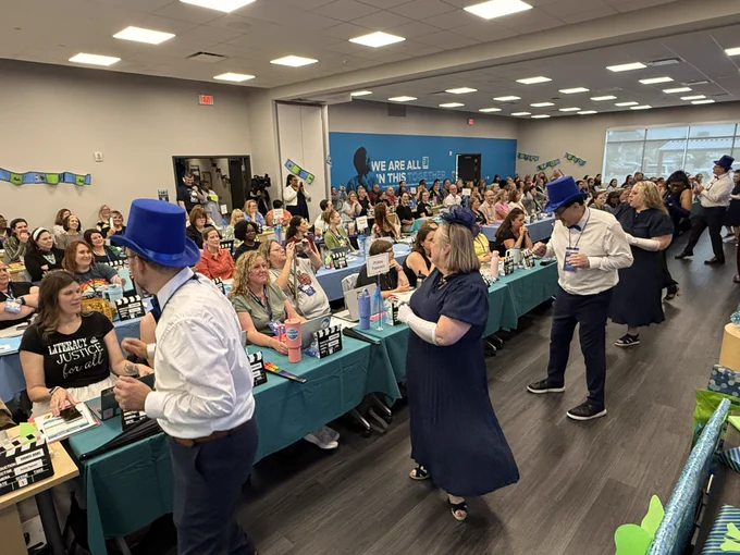 Adults dance in front of a room of library media specialists.