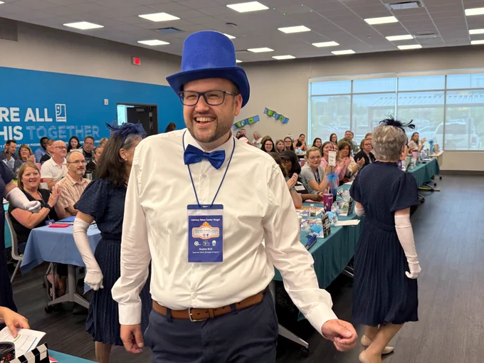 A man wearing a top hat smiles.