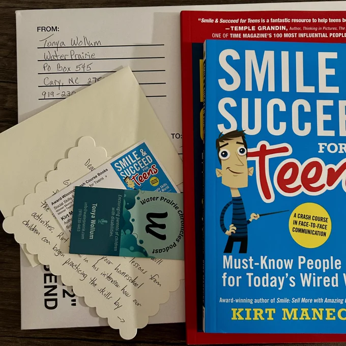 A photo of the SMILE & SUCCEED book and Parent’s Guide along with a handwritten letter and business cards sitting on top of a mailing envelope.