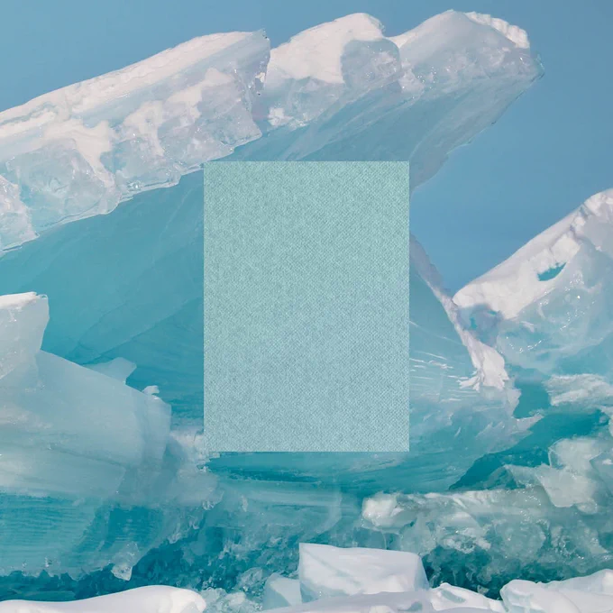 A large block of ice partially obscures a turquoise textured image against a backdrop of clear blue ice formations.