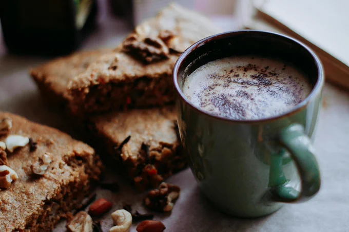 Delicious warm coffee served with slices of nutty carrot cake, perfect for a cozy treat.