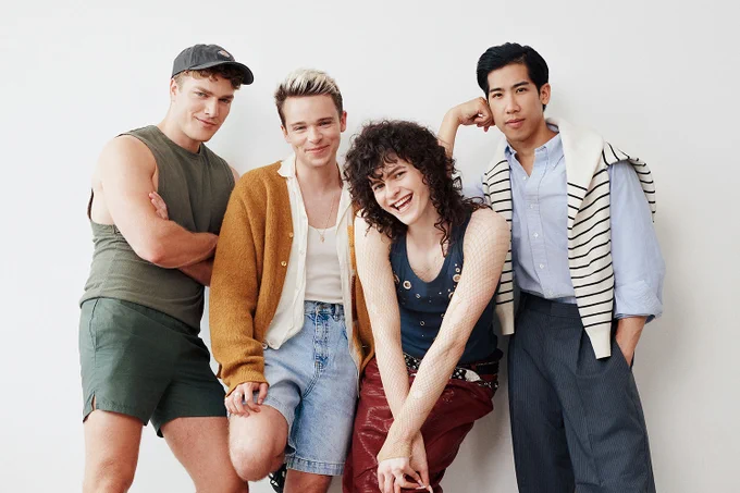 A photo showing four performers leaning against a wall 