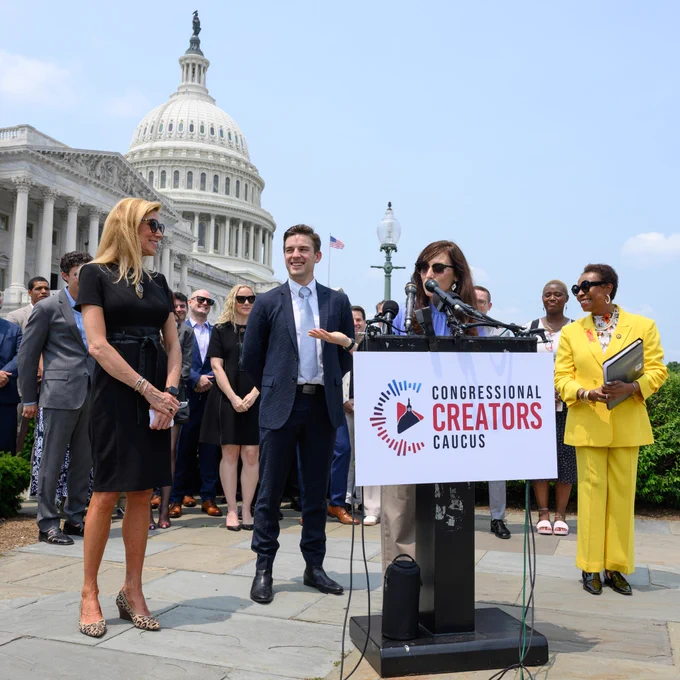 MatPat and Steph standing in front of the Capitol building giving a press conference alongside Rep. Van Dyune and Rep. Clarke. A bunch of YouTube creators stand behind them.