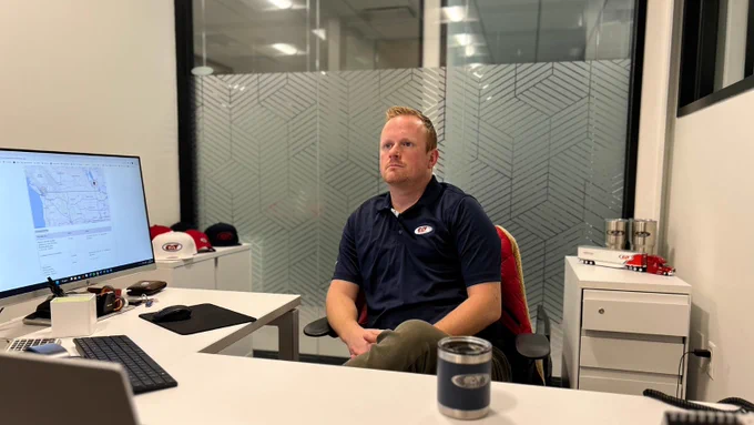 CAT Global employee focused on logistics tracking from a private office, surrounded by branded items and transportation models.