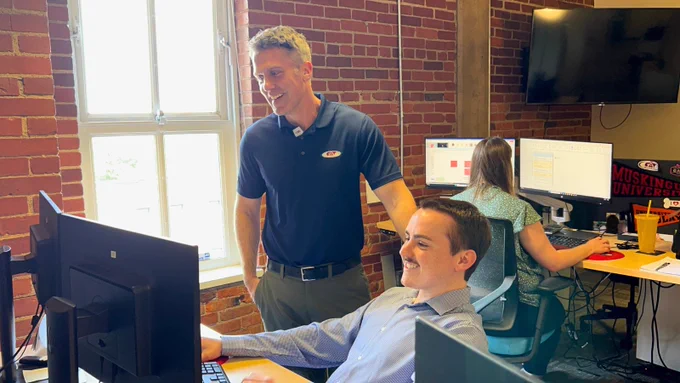 CAT Global team members collaborating at a workstation in a brick-wall office, reflecting teamwork and hands-on support in logistics.