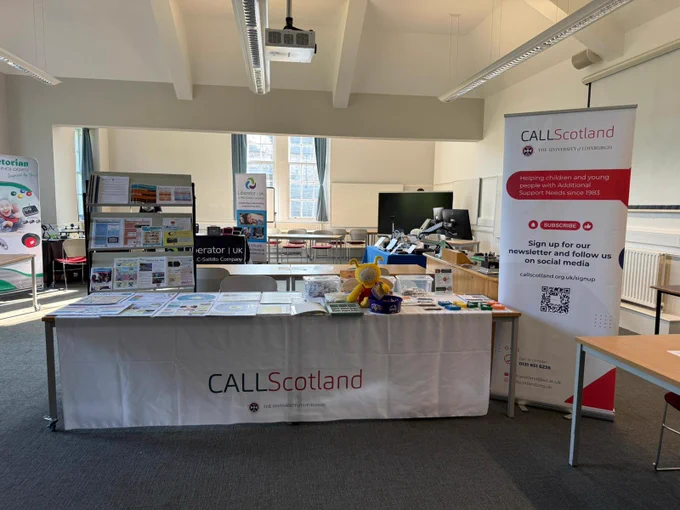 Photograph of an exhibition space with tables which have leaflets and assistive technology. A banner reads 'CALL Scotland'.