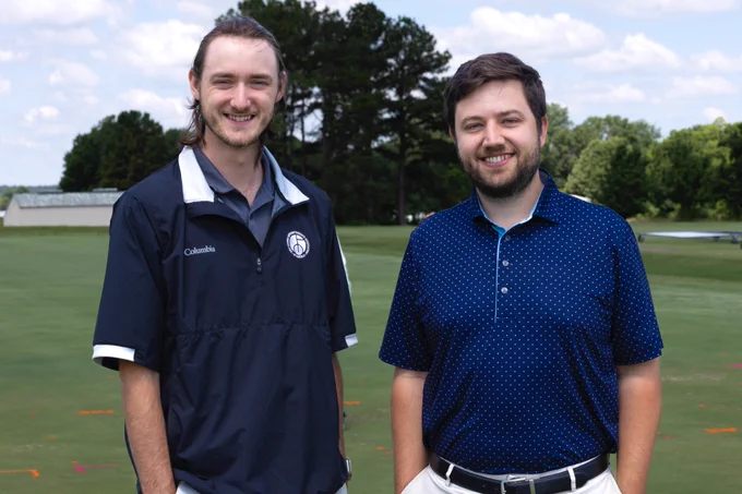Samuel Kreinberg and Wendell Hutchens standing and smiling on a green lawn.