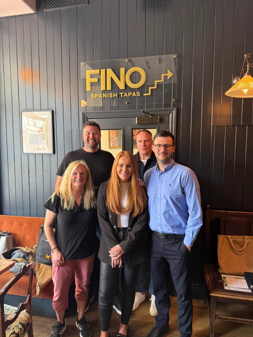 A picture of Liv Williams (centre front) with her  PhD supervisors, Jess Macbeth (front left), Andy Sprake (back left), Alan Thomson (back right), and External Examiner,  Anthony Maher (front right). All five are pictured standing together in a restaurant celebrating.