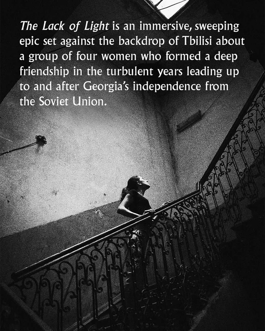 Black and white photo of a woman halfway up an old-fashioned staircase, looking up. Over it, white text reads: "The Lack of Light is an immersive, sweeping epic set against the backdrop of Tbilisi, about a group of four women who formed a deep friendship in the turbulent years leading up to and after Georgia's independence from the Soviet Union."