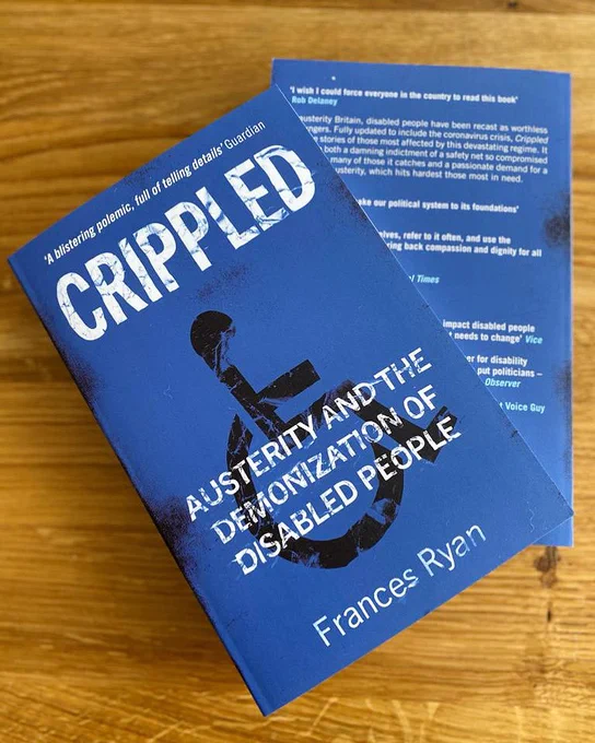 Two copies of Crippled sit on top of one another. The front cover is dark blue with white writing and has a black wheelchair symbol on it.