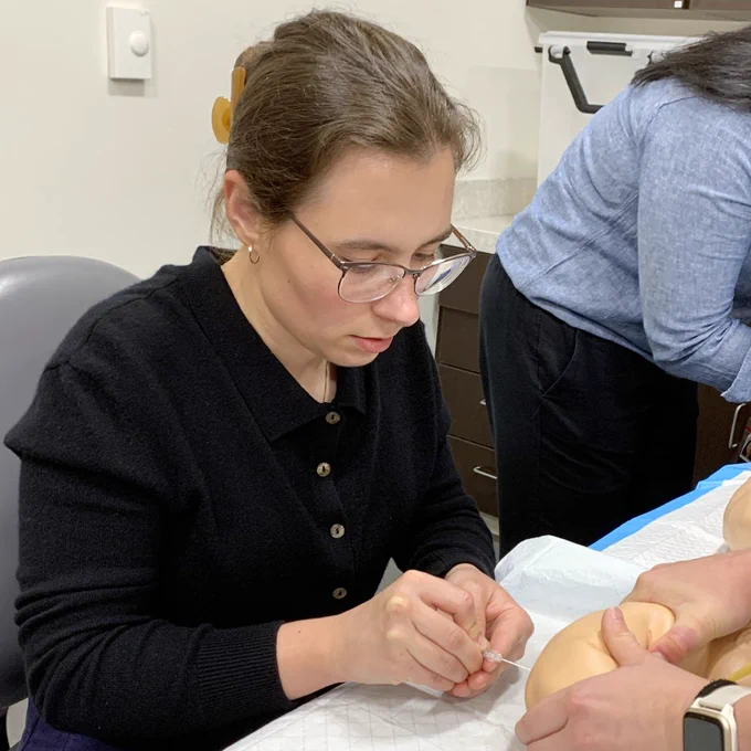 An intern practices a spinal tap on an infant simulation manikin.