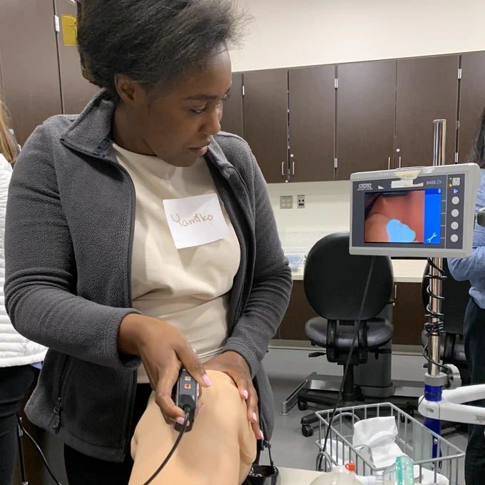 An intern uses a laryngoscope on a simulation manikin.