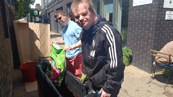 Two Share students pouring soil into a bag.