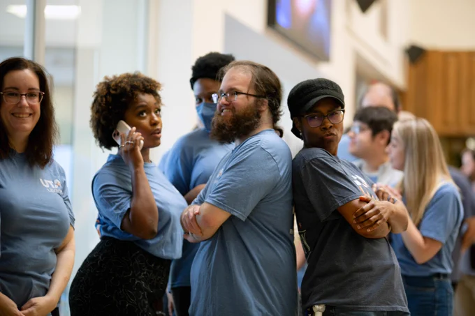 [ID: Pictured is a photo of UTA Libraries staff members waiting in line for food while having a little bit of fun striking a pose similar to the one from the TV and movie "Charlie's Angels."