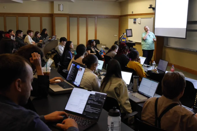 Students looking at computers as professor teaches.