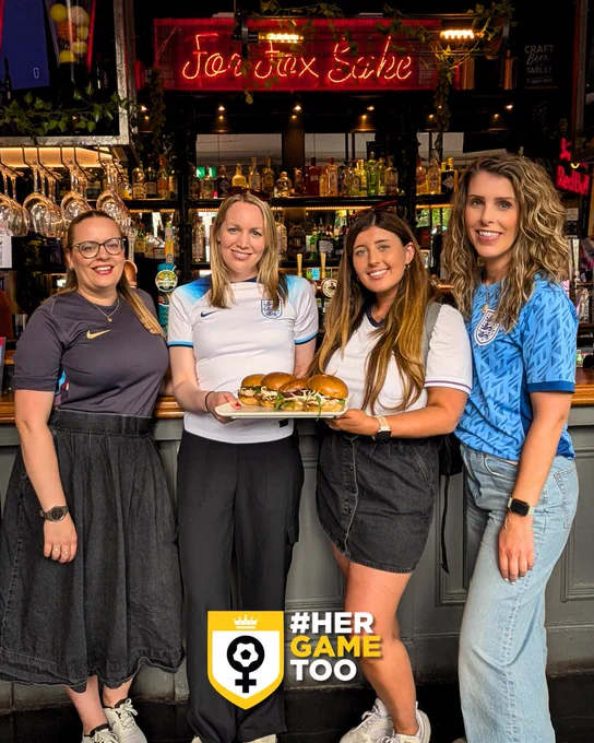 Four Her Game Too team members posing with 4 Russo chicken burgers in a pub setting