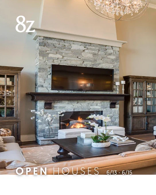 Elegant living room featuring a stone fireplace with a mounted television above, flanked by dark wood bookcases. A chandelier hangs overhead and a modern coffee table is situated in front. Promotional text "8z Open Houses 6/13-6/15" at the top.