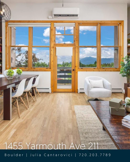 Interior of a modern room with large French doors leading to a balcony, showcasing a scenic mountain view. Features wooden floors, a cozy white armchair, and a dining area with a table and white chairs. The image includes contact information and address "1455 Yarmouth Ave 211, Boulder | Julia Cantarovici | 720.203.7789" at the bottom.