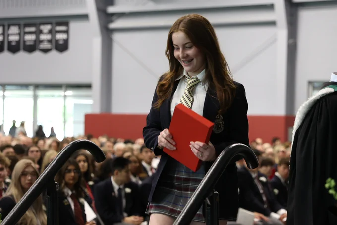 A student is smiling walking down stairs off stage after accepting an award.