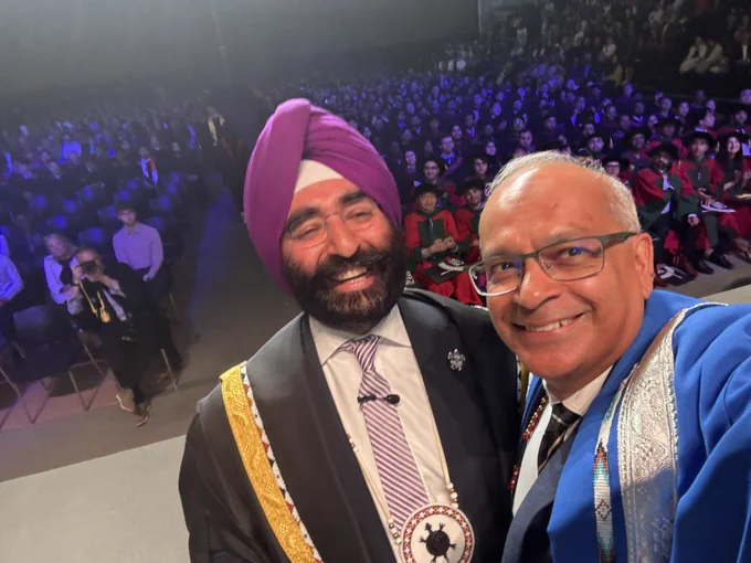 President Goel and Chancellor Bachher pose in front of the graduating class at Faculty of Engineering convocation inside the Physical Activity Complex.