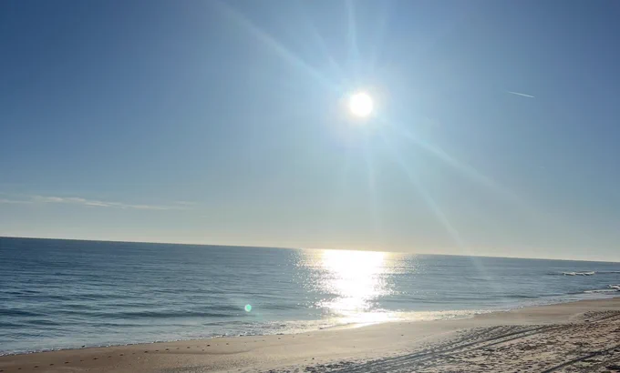 Sunrise over the Atlantic Ocean in Flagler Beach, Florida with soft light reflecting on calm water and sand.