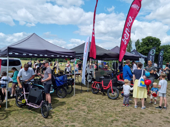 A range of cargo bike retailer stalls with many people talking and trying out bikes