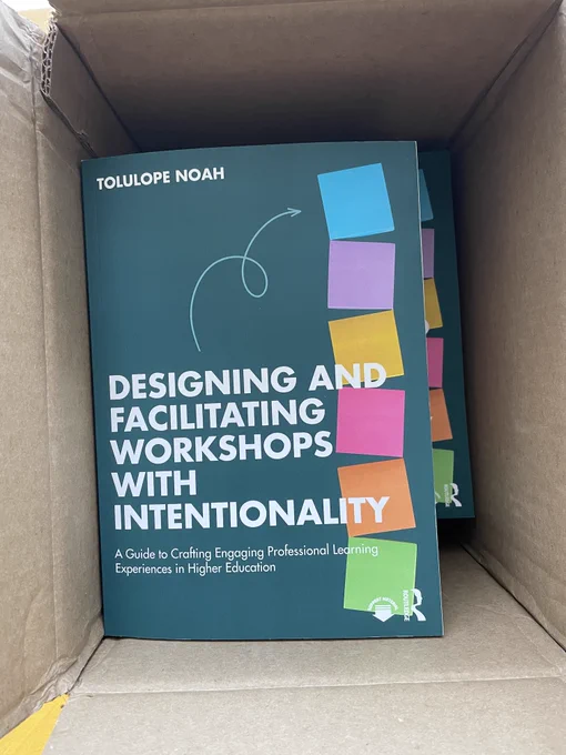 An open shipping box with copies of Tolu's new book, Designing and Facilitating Workshops with Intentionality, inside.