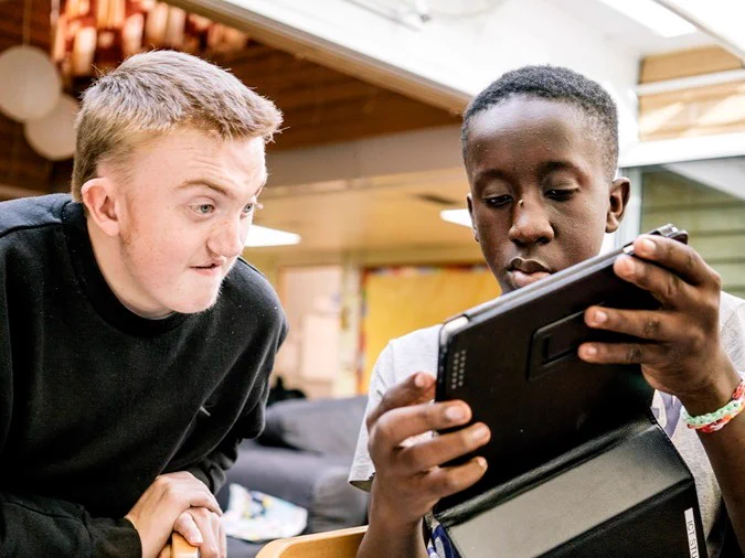 Two individuals closely looking at a tablet screen.