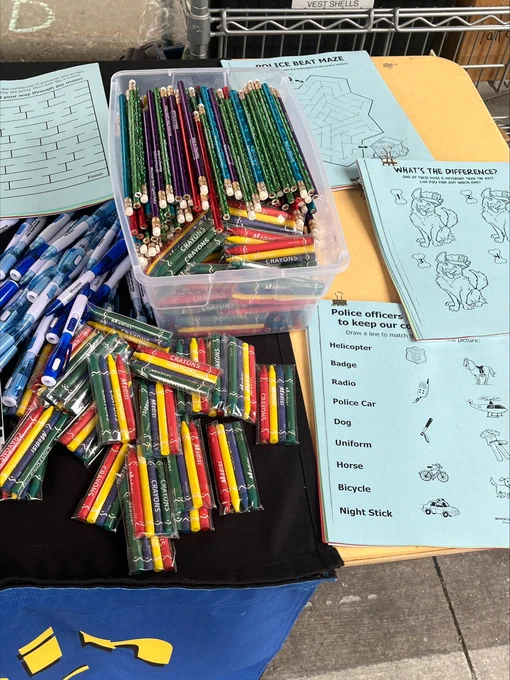 A variety of color pencils, pens, and coloring books with information about police officers and K-9 officers. 
