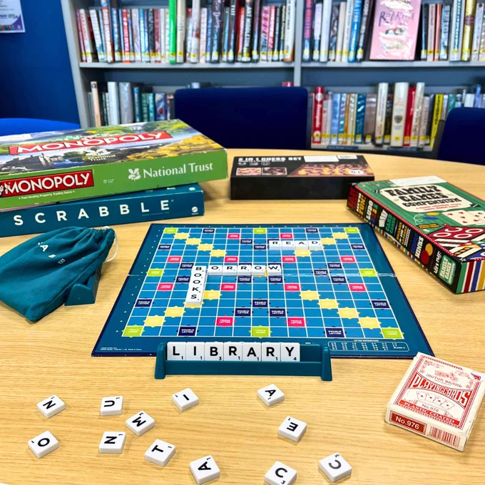 Photograph of board games at a table at Ash Library including Scrabble, Monopoly, cards etc.