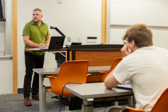 Virginia Tech ECE collegiate assistant professor Arthur Ball writes through an example problem for his circuits and devices class with one student taking notes.
