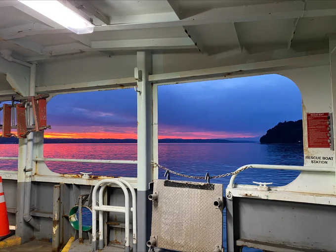Interior view of a ferry overlooking a sunset on the water.