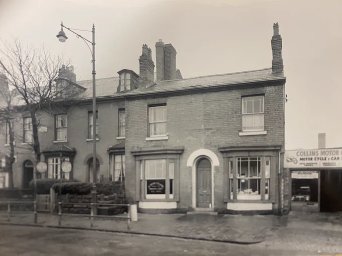 A street scene.  A row of terraced houses on the left of the photograph with the bare branches of a tree in front. A larger building at the end of the row of terraced houses in the middle of the photograph used as a business premises. A motorcycle shop on the far right of the photograph. 