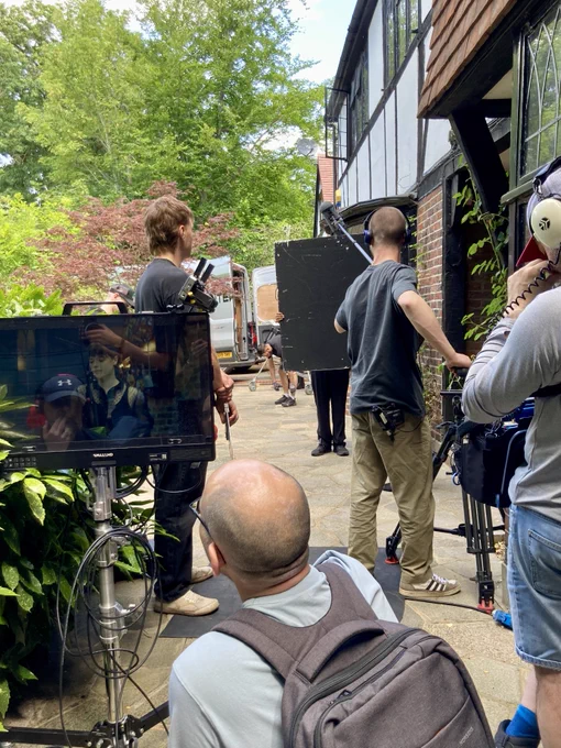 Cast and crew prepare for a shot of a woman outside a building.