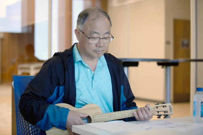 [ID: Pictured is a photo of a UTA Libraries staff member playing the ukulele.]