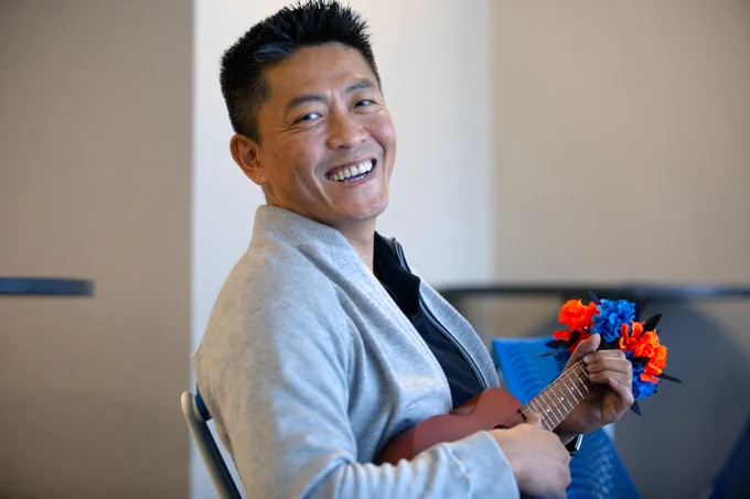 [ID: Pictured is a photo of a UTA Libraries staff member playing the ukulele.]